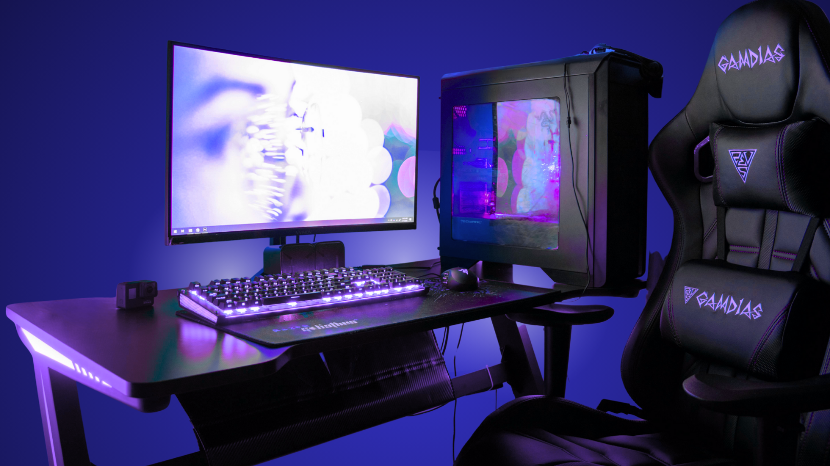 Gaming setup with monitor, keyboard, and chair in a dark room with blue lighting